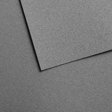 Close-up of dark gray textured foam panels overlapping at angle lines on a speckled surface.