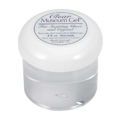 Small clear jar with a white lid labeled 'Clear Museum Gel' for securing glass and crystal; transparent gel inside.